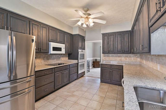 kitchen with white appliances, light stone counters, dark brown cabinets, and a sink