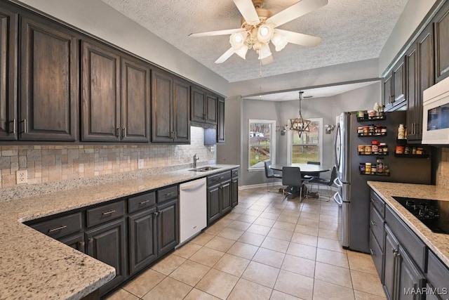 kitchen with pendant lighting, tasteful backsplash, a sink, light stone countertops, and white appliances