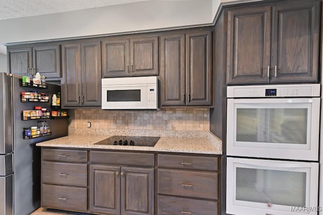 kitchen with light stone counters, white appliances, backsplash, and dark brown cabinetry