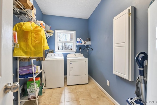 laundry area with light tile patterned floors, a textured ceiling, laundry area, baseboards, and washer and clothes dryer