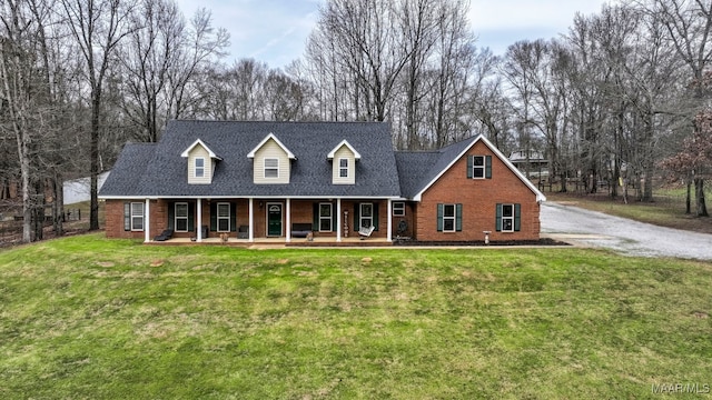 cape cod home featuring covered porch, brick siding, a front yard, and a shingled roof