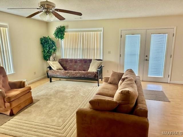 living room with a textured ceiling, french doors, a ceiling fan, and baseboards