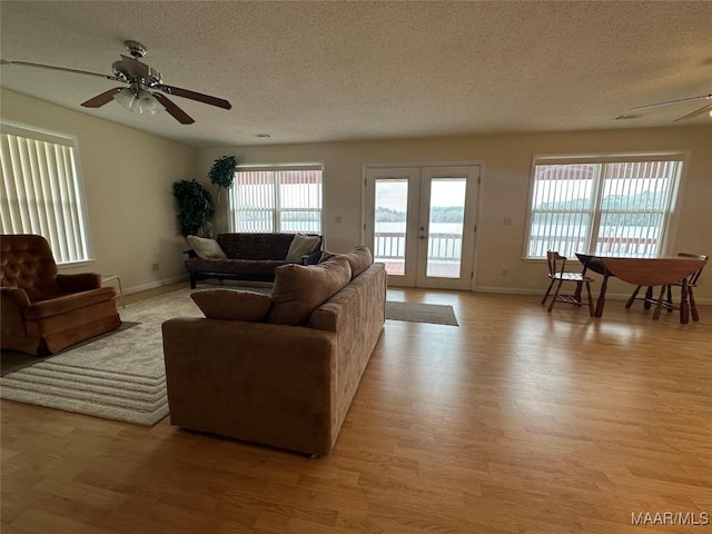 living area featuring light wood finished floors, ceiling fan, a textured ceiling, and french doors