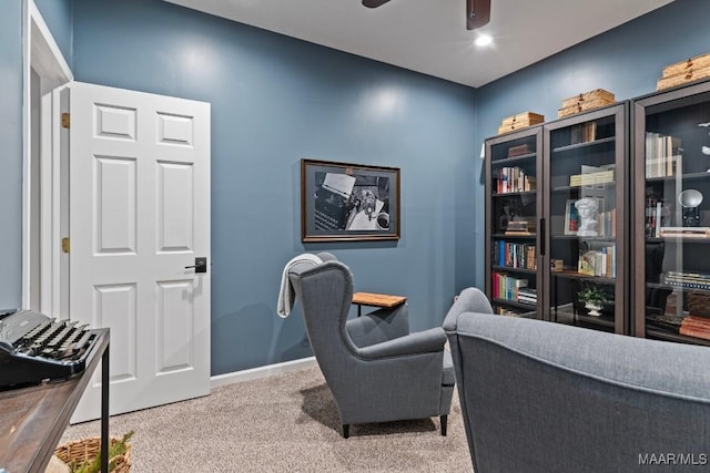 carpeted office space with a ceiling fan and baseboards