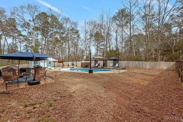 view of yard with a fenced in pool, a patio area, a fenced backyard, and an outdoor structure