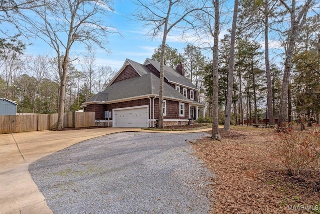 view of property exterior featuring driveway, a chimney, an attached garage, and fence