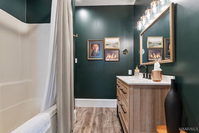 bathroom with shower / tub combo, baseboards, wood finished floors, and vanity