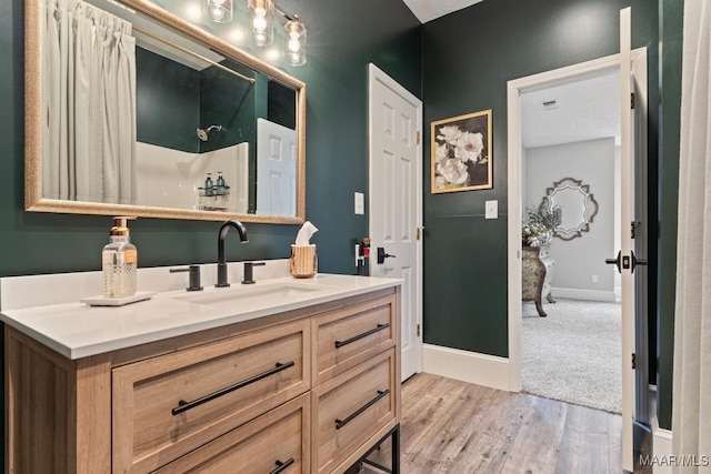 full bathroom featuring visible vents, vanity, wood finished floors, baseboards, and walk in shower