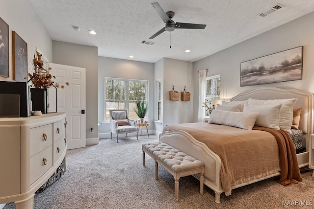 carpeted bedroom featuring a ceiling fan, visible vents, and a textured ceiling