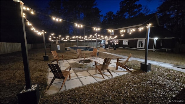 patio at night with an outdoor fire pit, a fenced in pool, and a fenced backyard