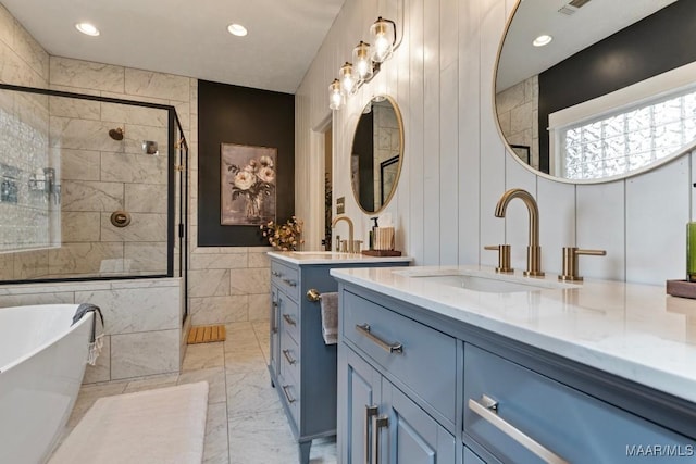 full bath featuring marble finish floor, a soaking tub, two vanities, a stall shower, and a sink