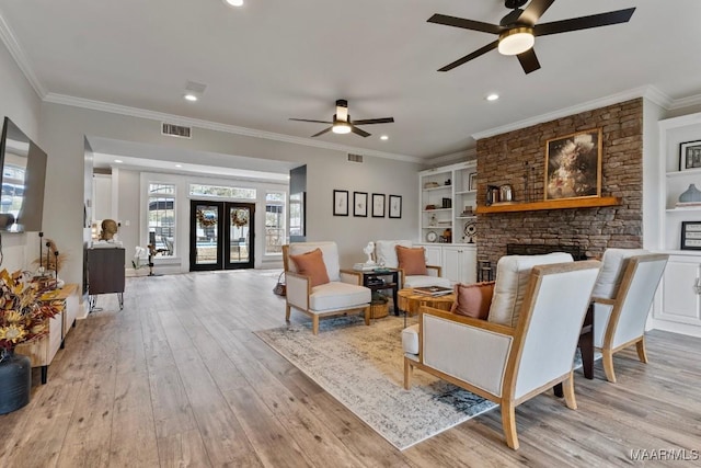 living area with light wood-style flooring, a fireplace, visible vents, ornamental molding, and french doors