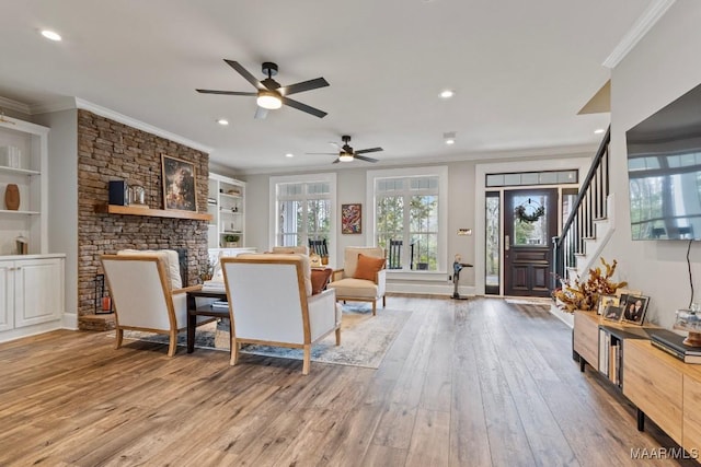 living room with crown molding, a fireplace, recessed lighting, stairway, and wood finished floors