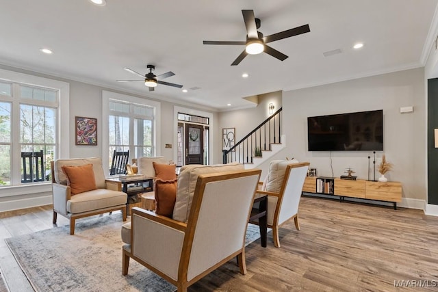 living area with ornamental molding, stairway, and light wood-style flooring