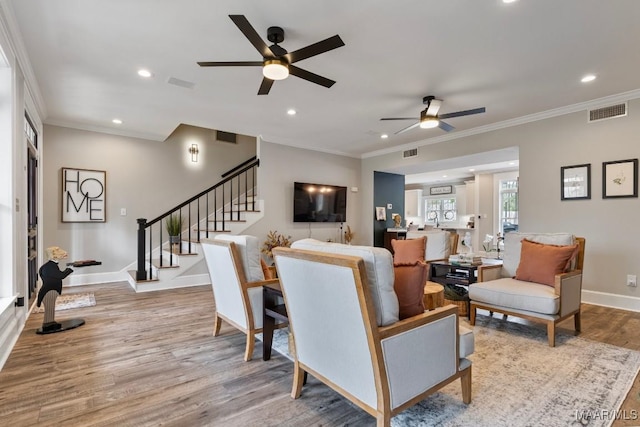 living room featuring stairs, ornamental molding, visible vents, and light wood-style flooring