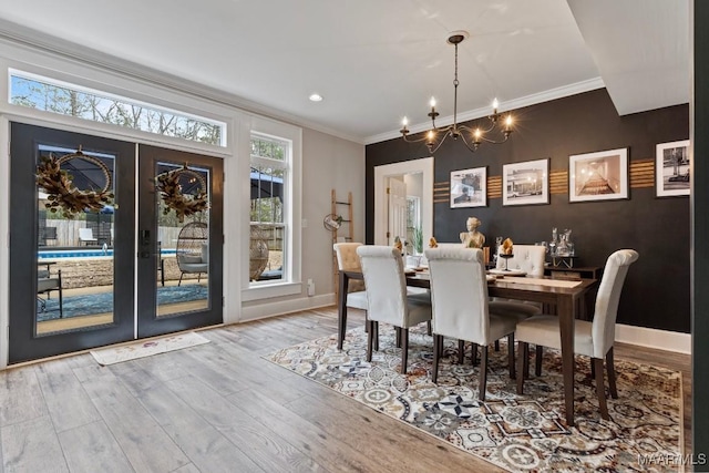 dining space featuring french doors, crown molding, light wood-style flooring, and baseboards