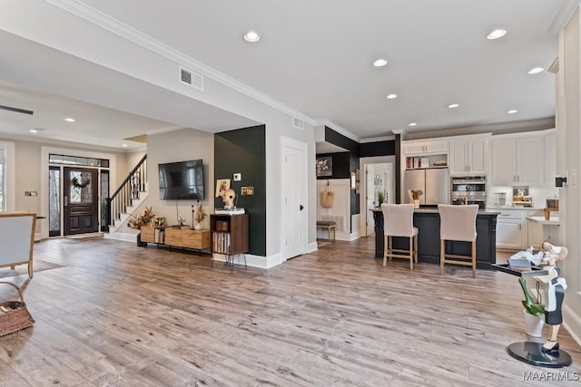 living area featuring light wood-style floors, baseboards, stairway, and visible vents