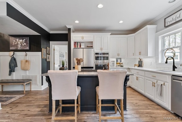 kitchen featuring visible vents, white cabinets, appliances with stainless steel finishes, a kitchen breakfast bar, and light countertops