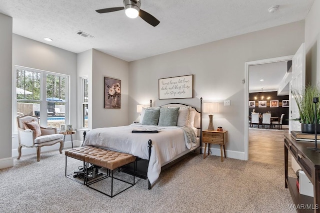 bedroom featuring a textured ceiling, carpet flooring, a ceiling fan, visible vents, and baseboards