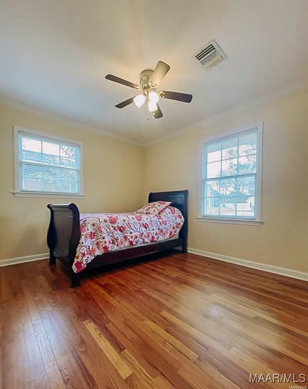 bedroom featuring ornamental molding, multiple windows, and visible vents