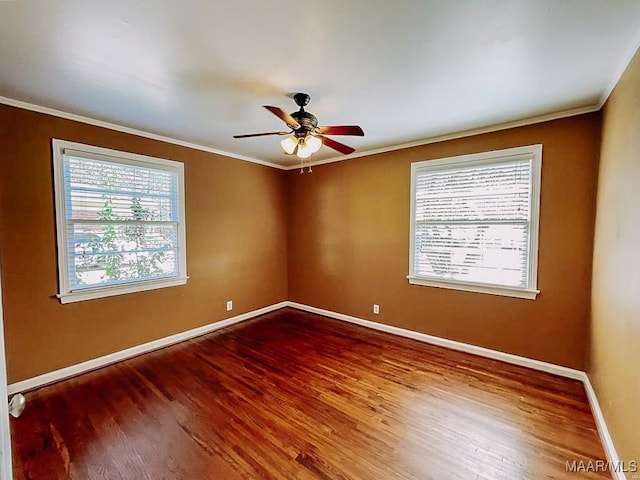 spare room featuring ornamental molding, a wealth of natural light, baseboards, and wood finished floors