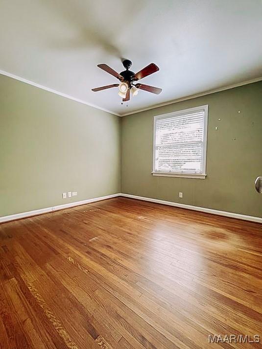 empty room featuring ceiling fan, baseboards, crown molding, and wood finished floors