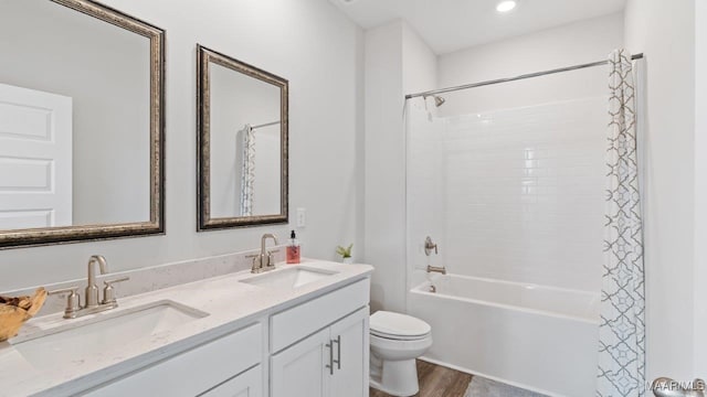 bathroom with double vanity, shower / tub combo, toilet, and a sink
