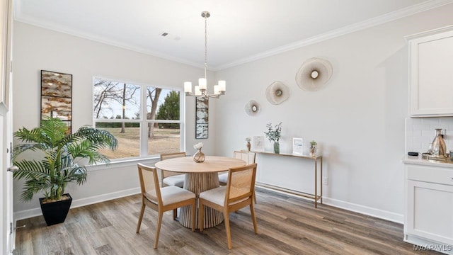 dining room with wood finished floors, ornamental molding, and a chandelier
