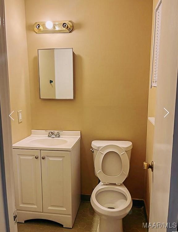 bathroom featuring baseboards, vanity, and toilet