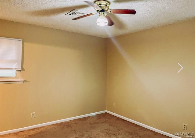 carpeted empty room with ceiling fan, a textured ceiling, visible vents, and baseboards