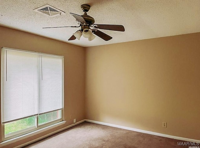 spare room with light carpet, baseboards, visible vents, and a textured ceiling