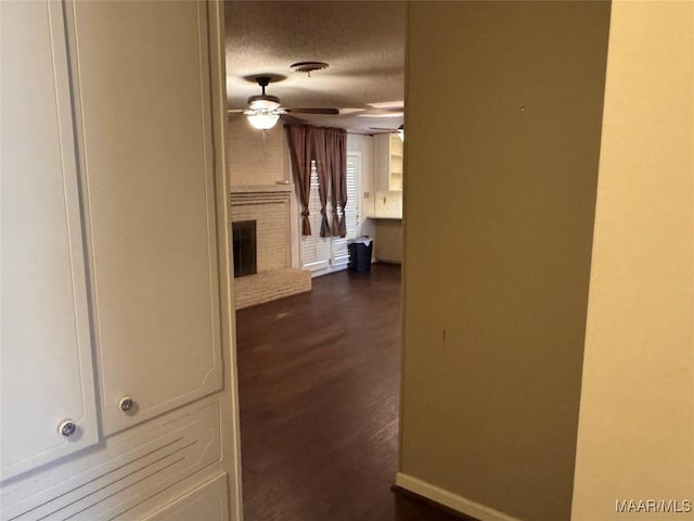 hallway featuring a textured ceiling, dark wood-type flooring, and baseboards