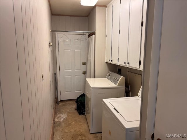 laundry room featuring cabinet space, separate washer and dryer, and wood walls