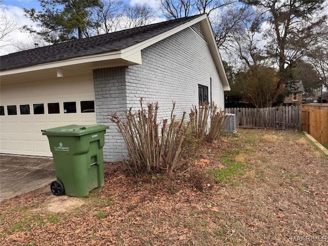 view of side of home with a garage, brick siding, and fence