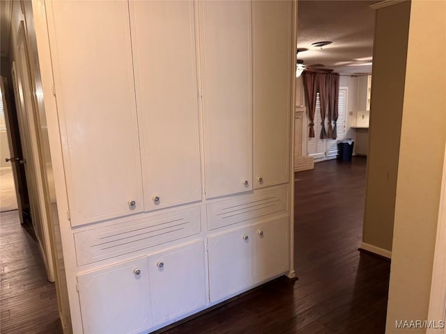 corridor featuring baseboards and dark wood-style flooring