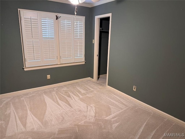 spare room featuring baseboards, ornamental molding, and light colored carpet