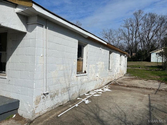 view of property exterior featuring a patio and concrete block siding