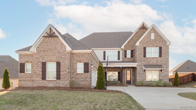 view of front facade featuring brick siding, a front yard, fence, and a shingled roof