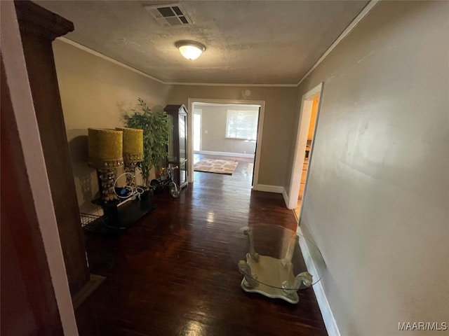 hallway featuring baseboards, visible vents, ornamental molding, dark wood-style flooring, and a textured ceiling