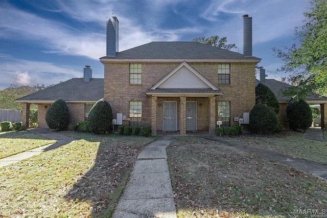 view of front of home with a shingled roof, brick siding, and a chimney