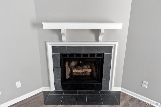 interior details featuring baseboards, wood finished floors, and a tile fireplace