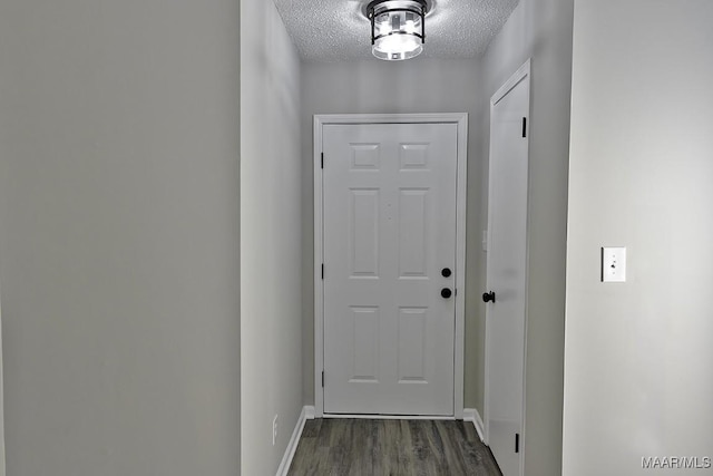 doorway to outside with a textured ceiling, dark wood-style floors, and baseboards