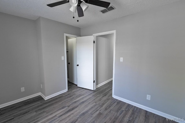 unfurnished bedroom with baseboards, a textured ceiling, visible vents, and dark wood-style flooring