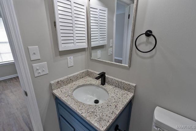 bathroom featuring toilet, wood finished floors, vanity, and baseboards