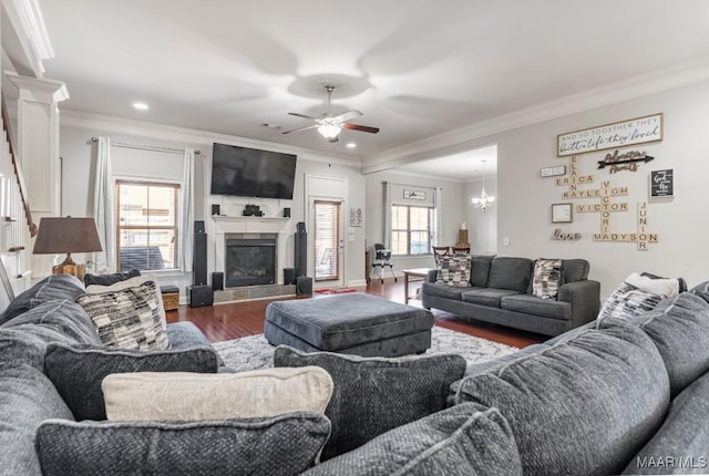 living area featuring wood finished floors, recessed lighting, a fireplace, ornamental molding, and ceiling fan with notable chandelier