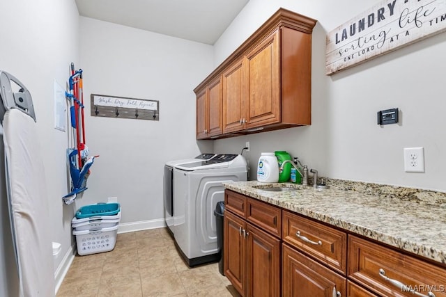 laundry room with a sink, cabinet space, light tile patterned flooring, baseboards, and washing machine and clothes dryer