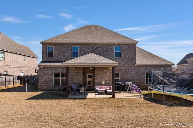 back of property featuring a patio, a fenced backyard, a shingled roof, a trampoline, and brick siding