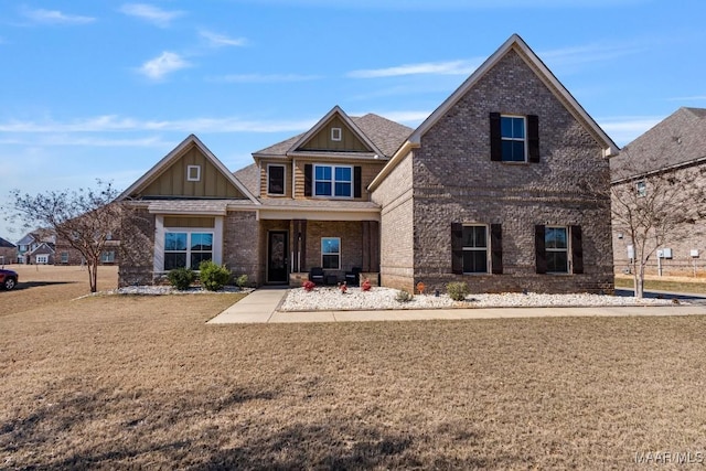 view of front of house featuring board and batten siding, a front yard, brick siding, and roof with shingles