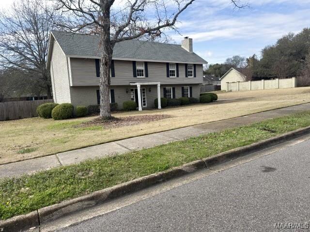 colonial home featuring a chimney, a front yard, and fence