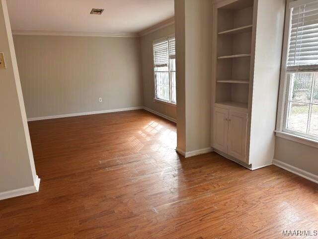 3110 Highfield Dr, Montgomery, AL 36111 - spare room featuring baseboards, built in shelves, ornamental molding, and wood finished floors